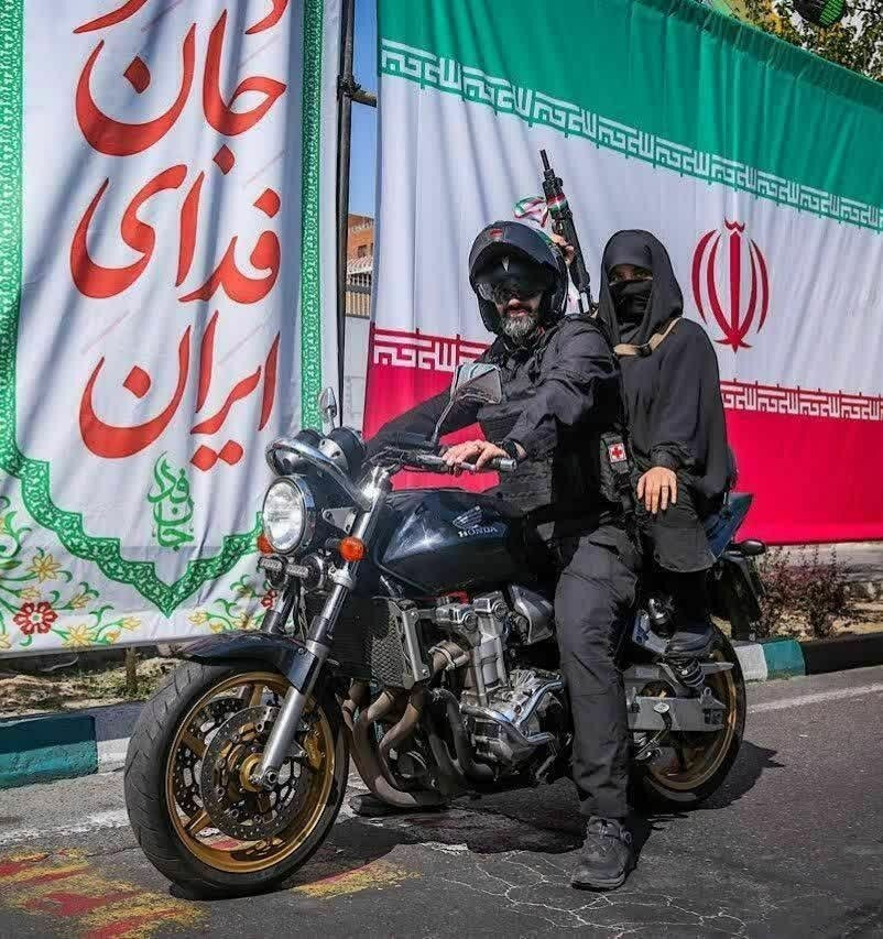 عکس | یک تصویر متفاوت؛ زن سلاح‌بدست ترک‌موتور نیروی نظامی ایرانی در کنار پرچم جمهوری اسلامی ایران